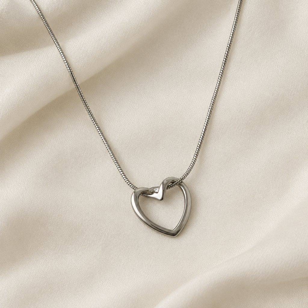 Silver-tone heart pendant necklace resting on cream fabric