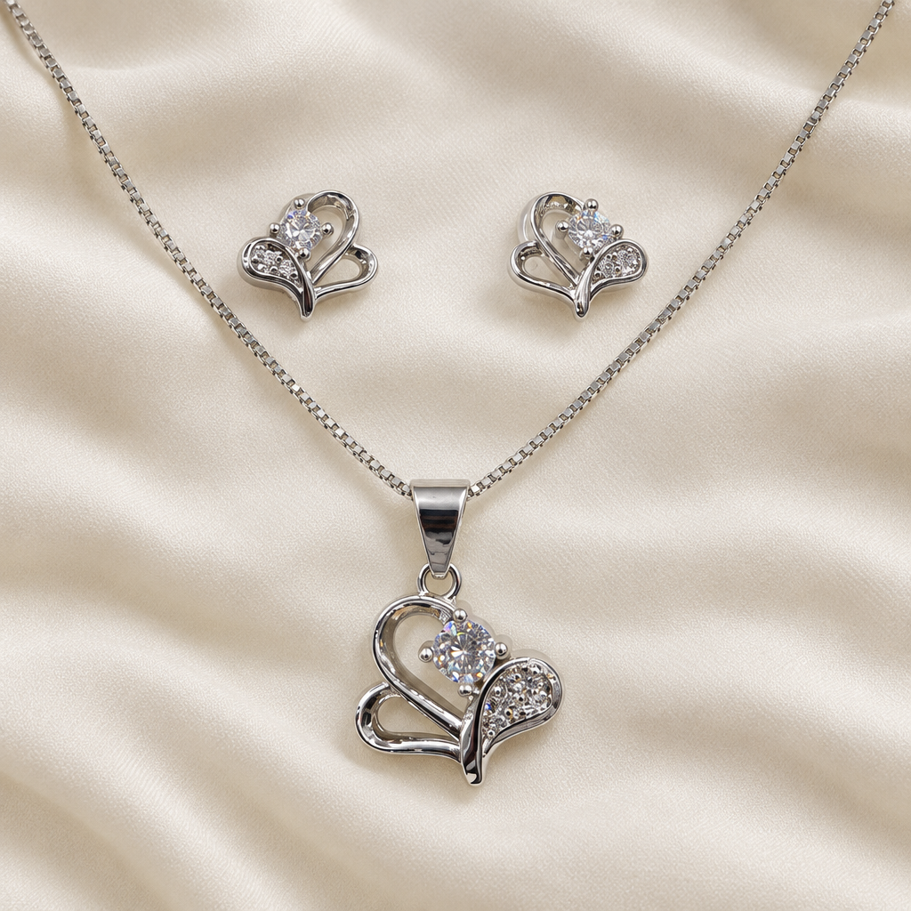 Silver-tone heart pendant necklace and matching studs on ivory fabric