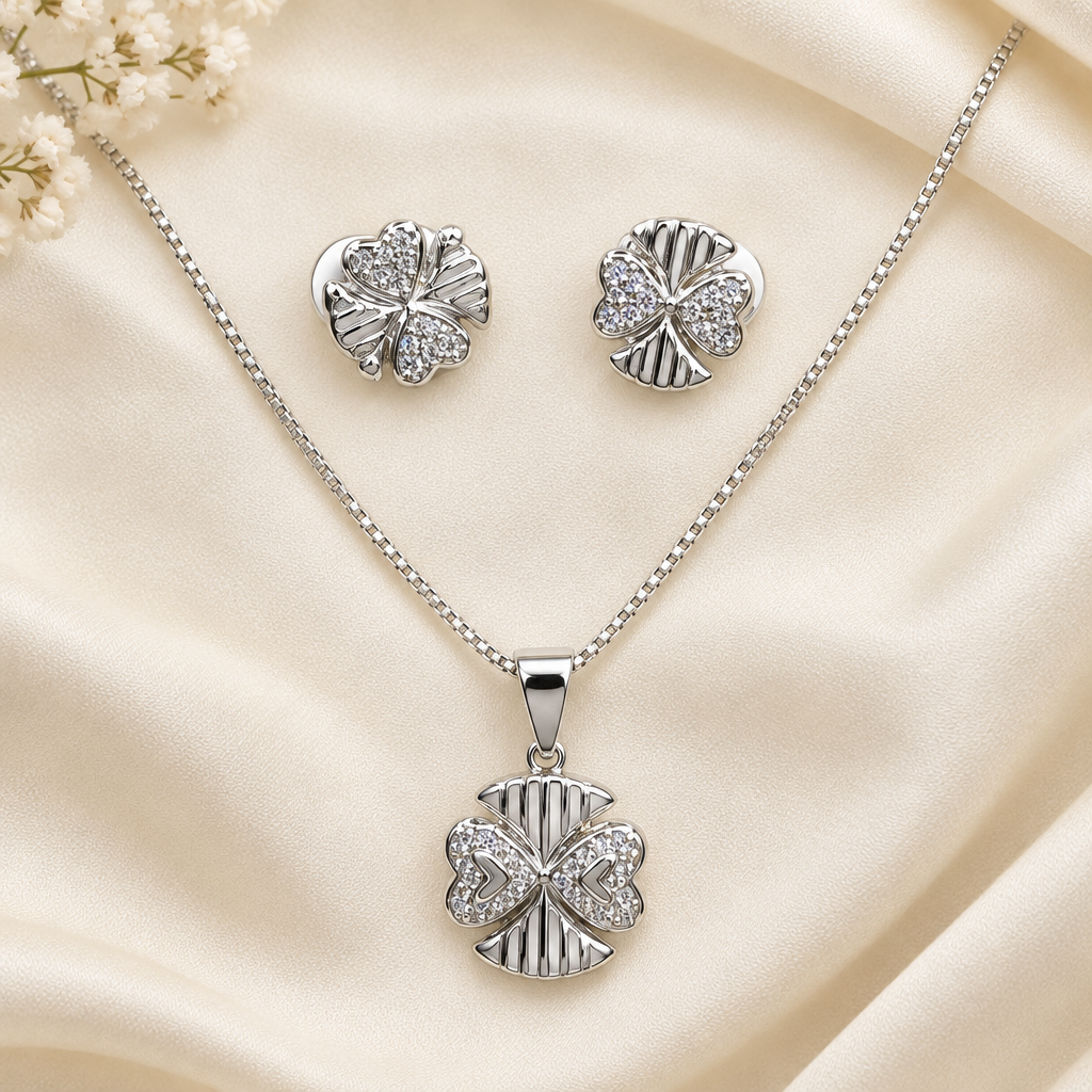 Silver-tone necklace and matching studs arranged on cream fabric