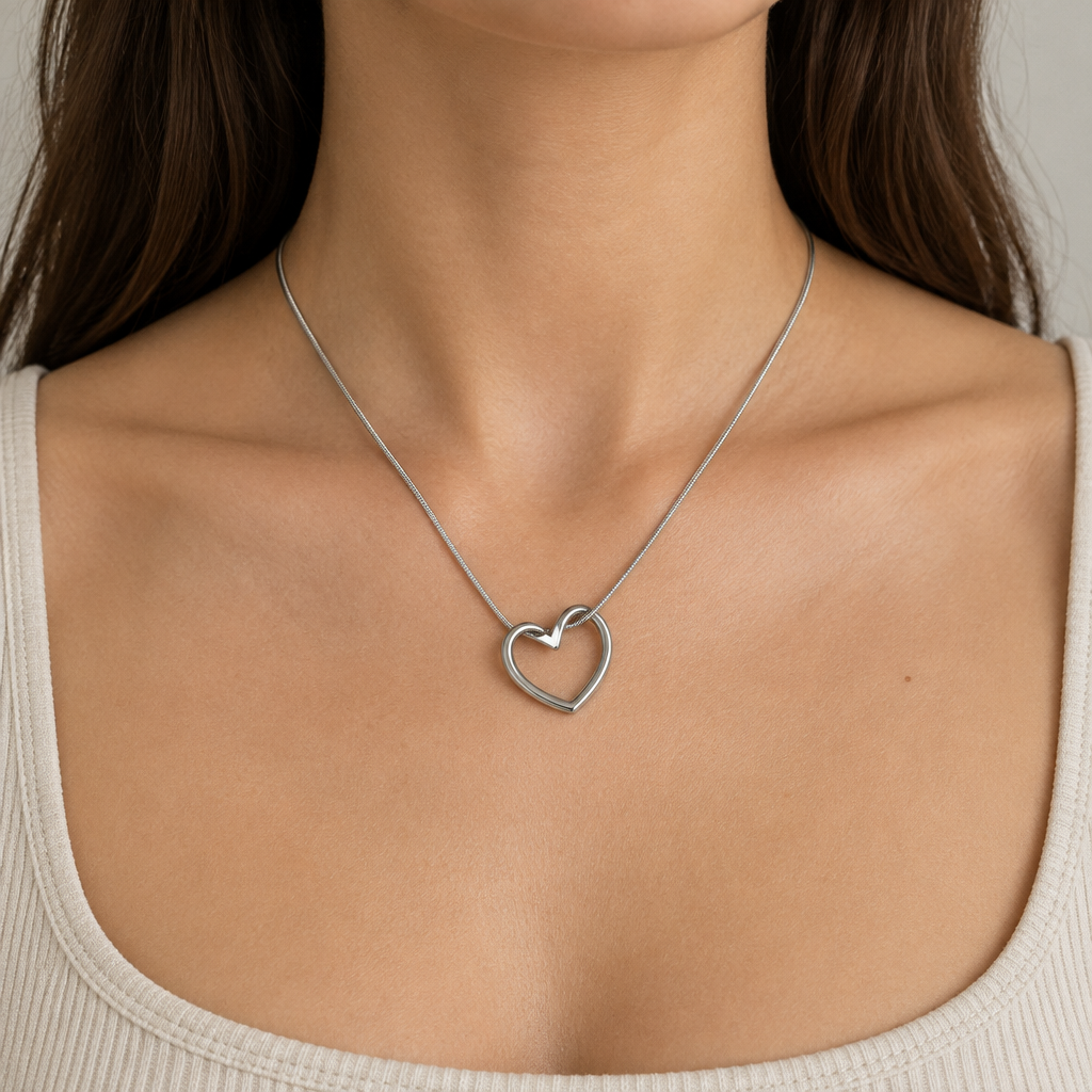 Model wearing a silver-tone open heart pendant necklace with a light outfit