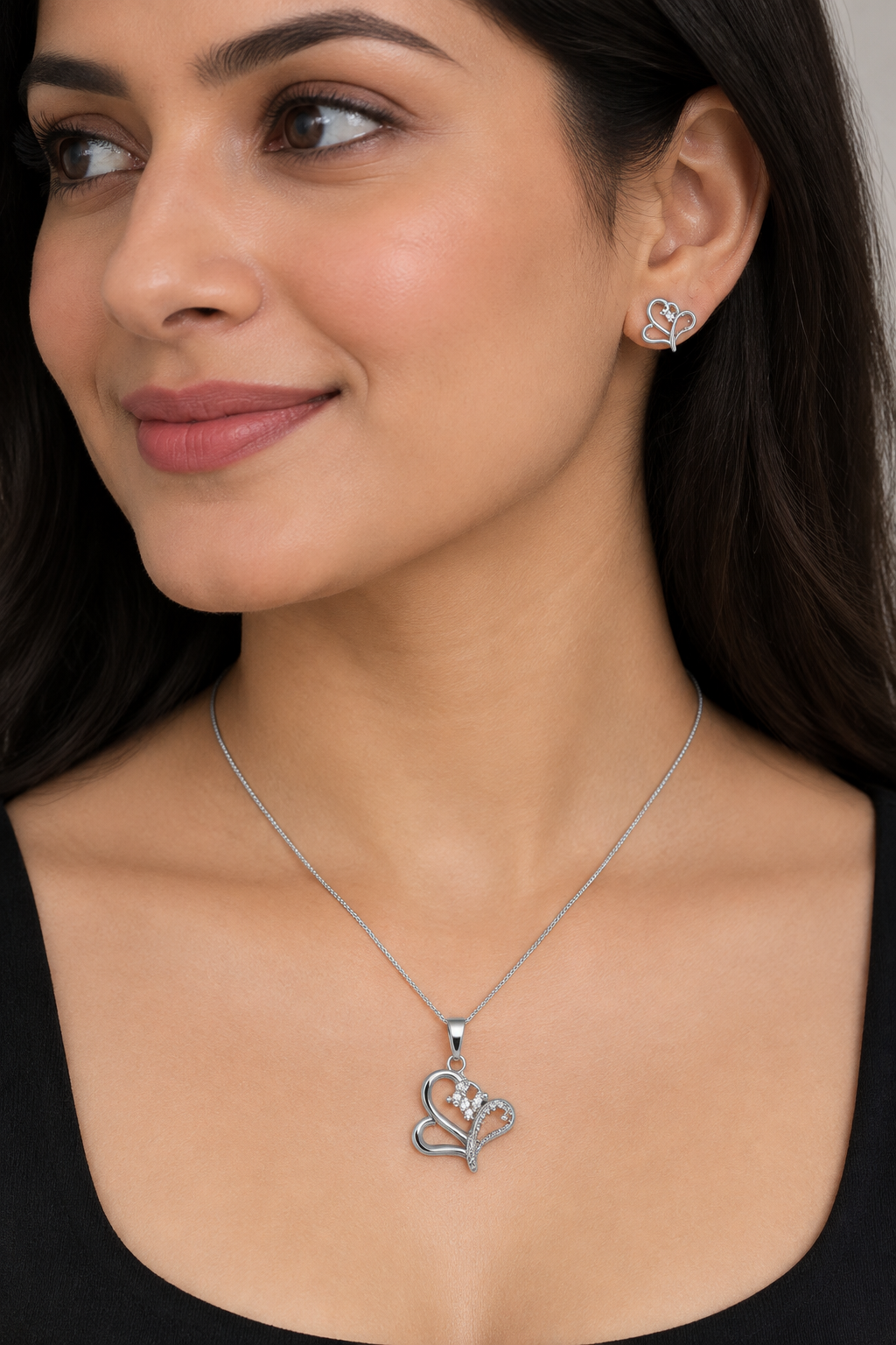 Styled model wearing curved heart pendant necklace and matching stud earring