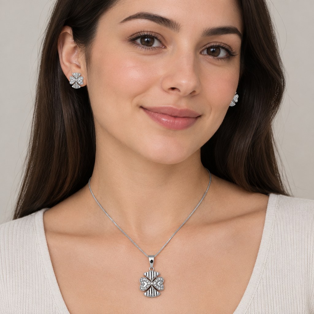 Model wearing four-petal silver-tone pendant and matching stud earrings with a light outfit