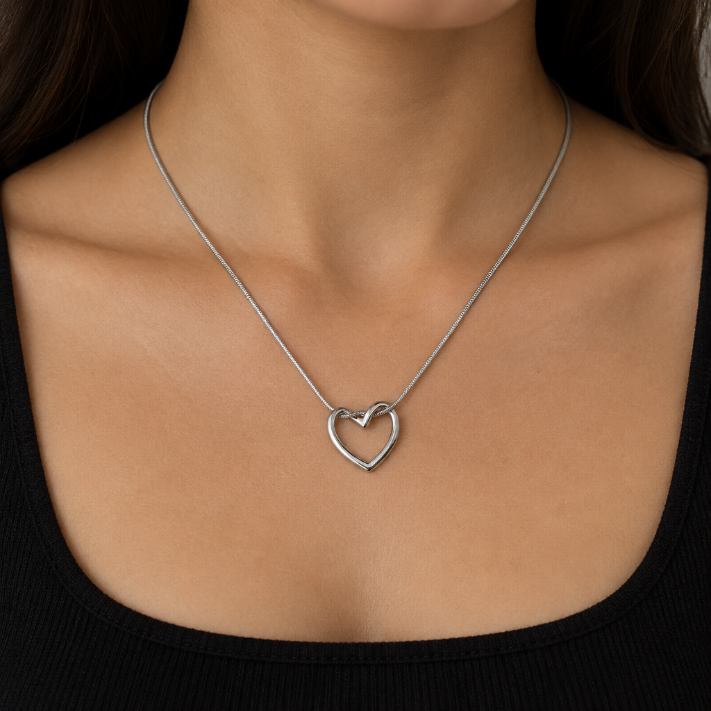 Model wearing a silver-tone open heart pendant necklace with a dark outfit