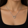 Model wearing a silver-tone open heart pendant necklace with a dark outfit