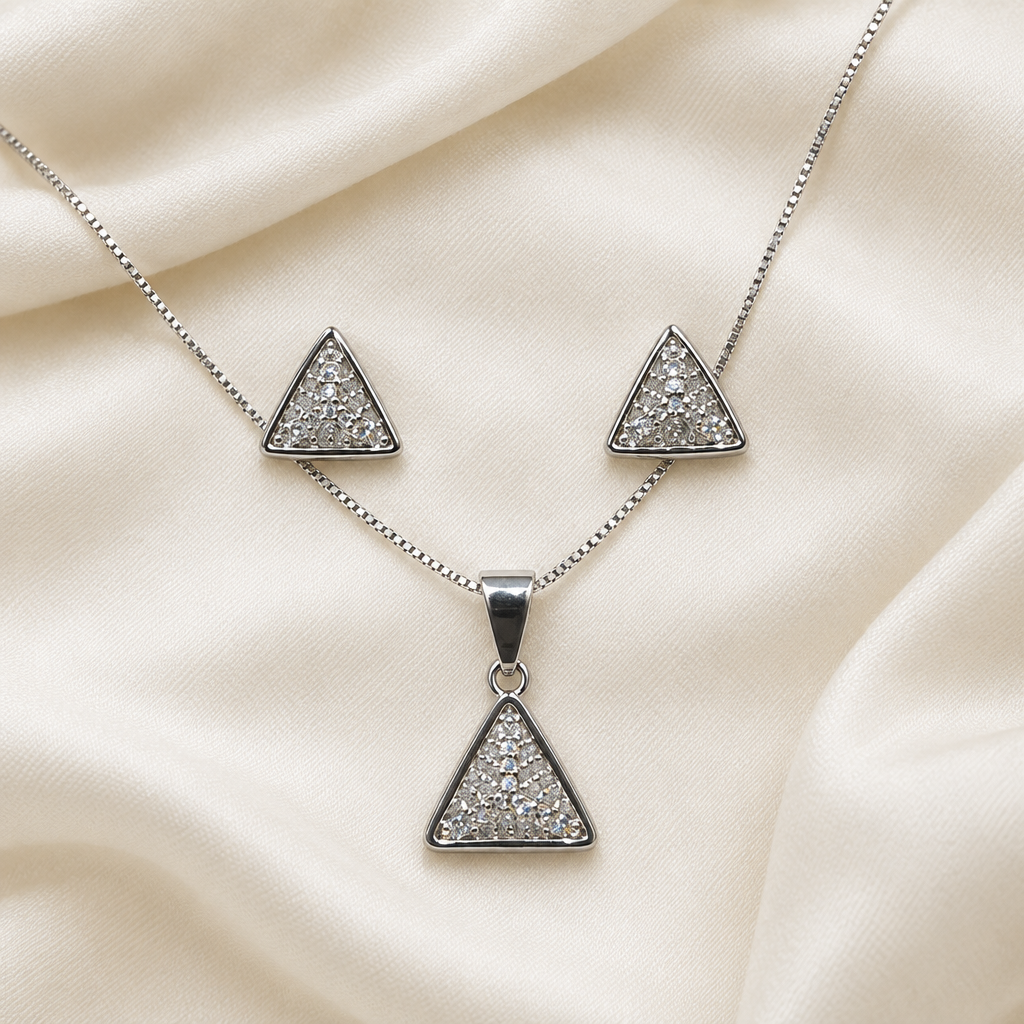 Silver-tone triangle pendant necklace and matching studs laid on ivory fabric