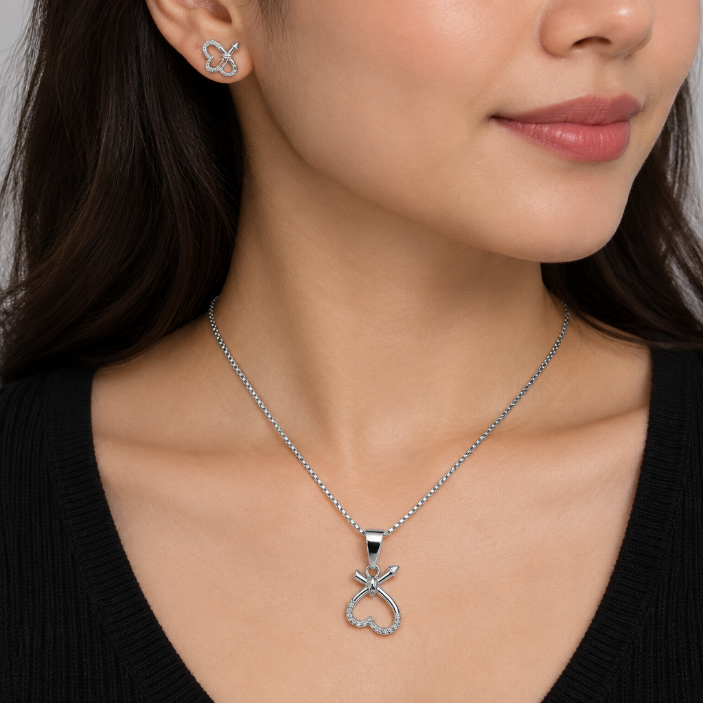 Model in dark top wearing silver-tone heart-loop pendant and matching earring